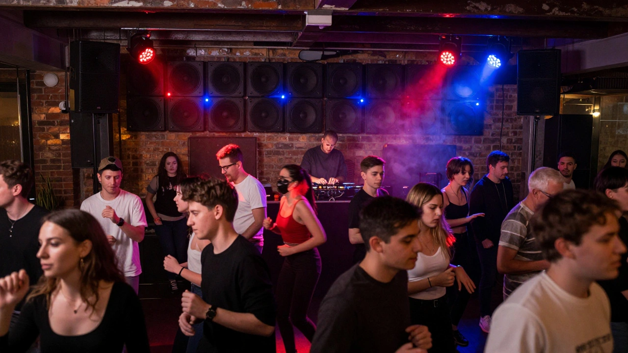 Diverse crowd dancing together on the packed floor of Electric Brixton under flickering red and blue lights, speakers lining the walls.